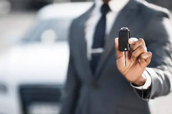 businessman-showing-car-key-against-luxury-auto-2023-11-27-05-18-06-utc.webp - Drive Deals